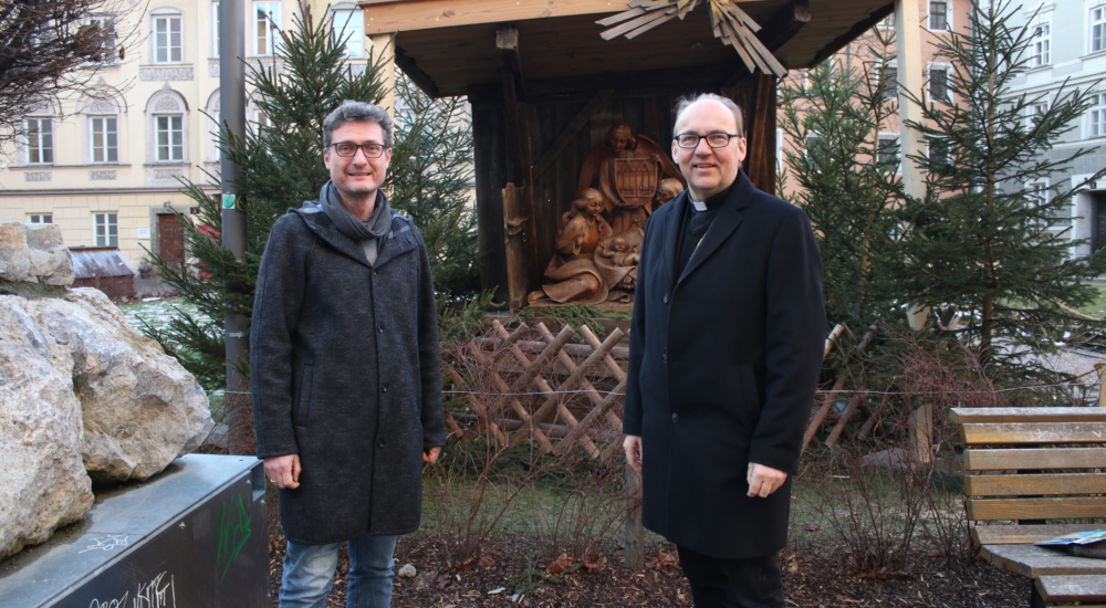 Zwei Männer vor religiösem Denkmal im Wald in Innsbruck