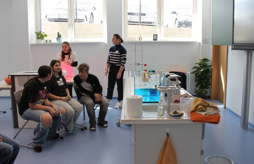 drei jugendliche sitzen vor der Experimente-Station und reden interessiert miteinander