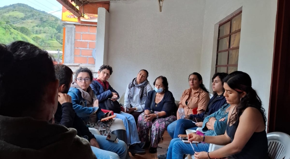 mehrere Menschen sitzen auf Terrasse zusammen und diskutieren miteinander
