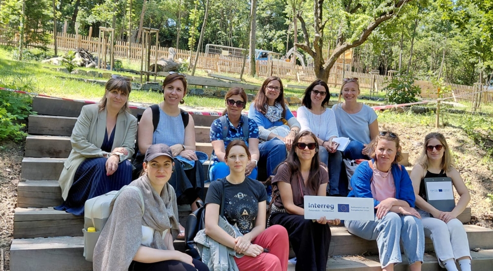 Die Gruppe von zehn Frauen lächelt in die Kamera und hält ein interreg Schild hoch
