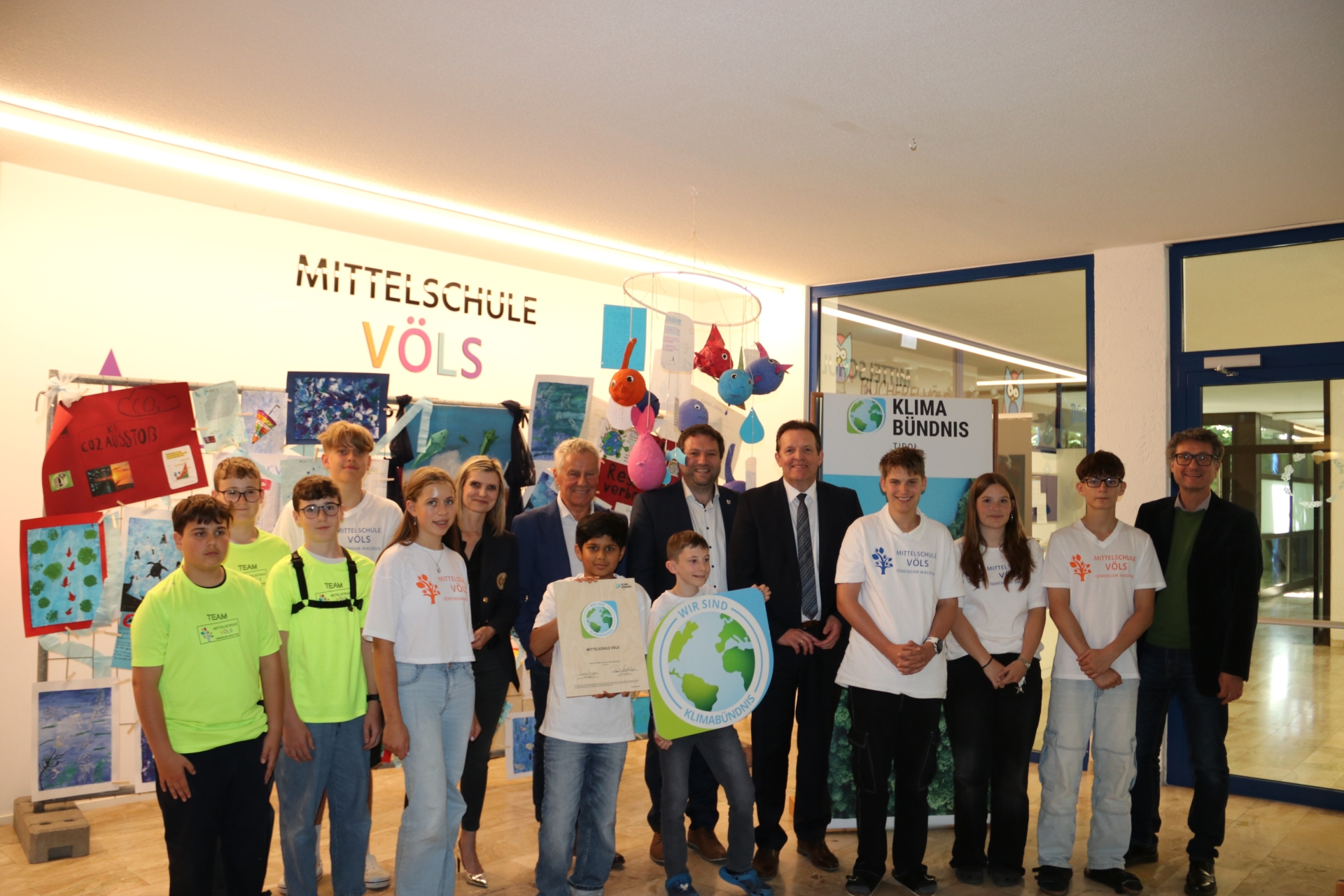 Gruppenfoto von Kindern und Erwachsenen mit Urkunden und einem Schild mit dem Logo des Klimabündnis