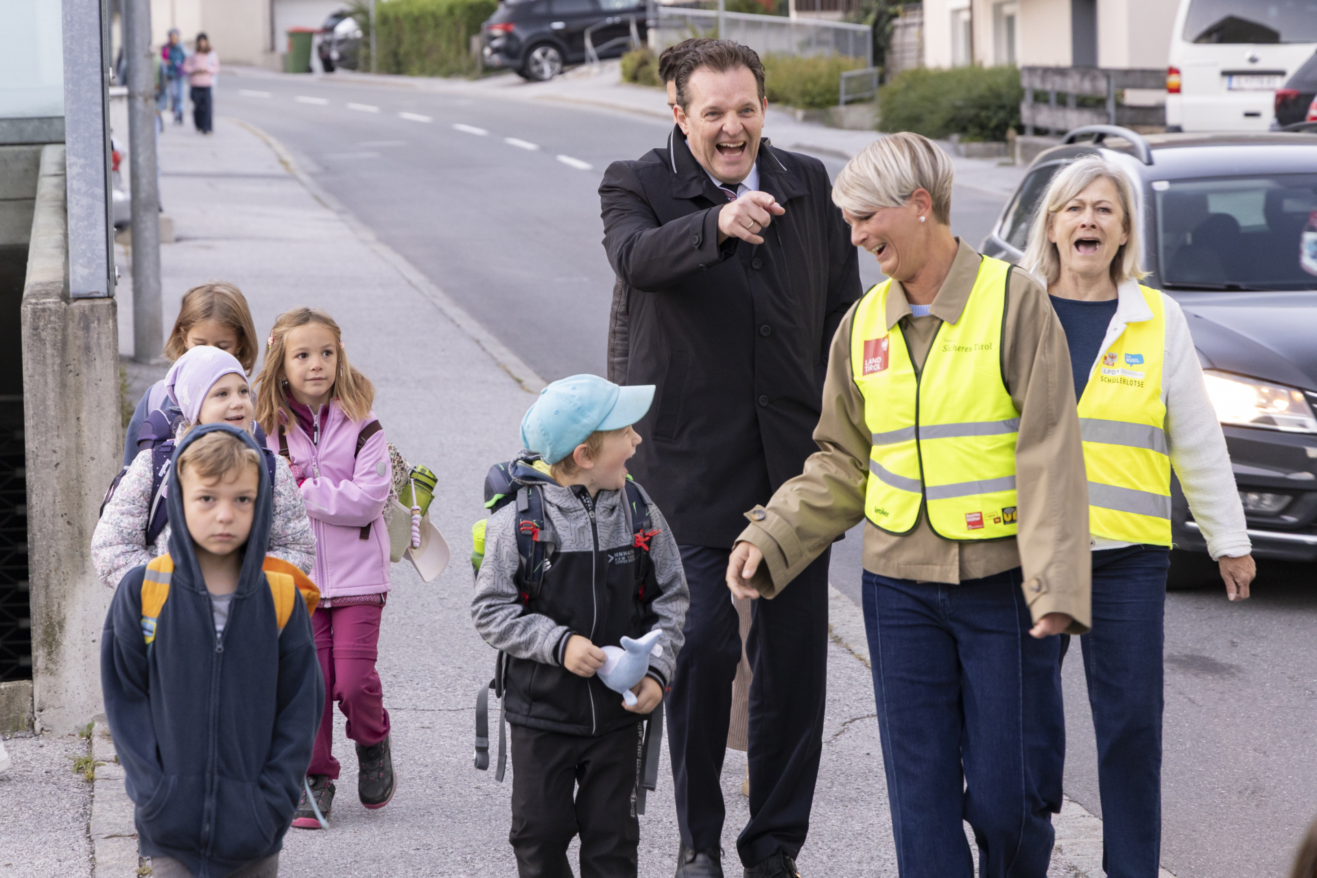 Kinder und Erwachsene, Teils mit Signalwesten, gehen am Gehsteig